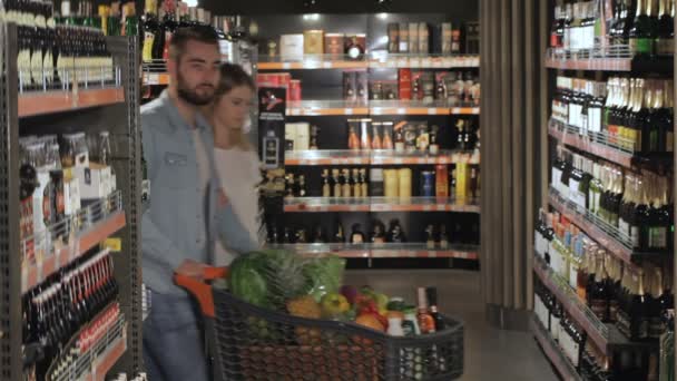 Casal escolhe álcool no hipermercado — Vídeo de Stock