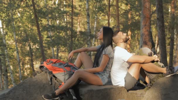 Un par de excursionistas se sienta espalda con espalda en la roca — Vídeos de Stock