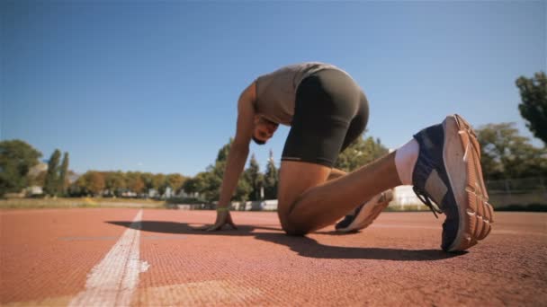 Mannelijke athlet is in de positie instellen aan het begin van de baan — Stockvideo