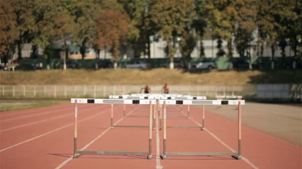 Δύο αθλητές που τρέχουν σε μικρή απόσταση με εμπόδια στο στάδιο — Αρχείο Βίντεο