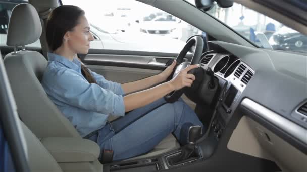 La mujer se sienta dentro del coche en el concesionario — Vídeos de Stock