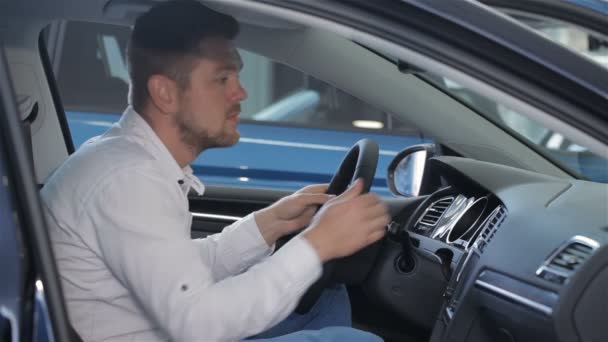 Homem examina o interior do carro na concessionária — Vídeo de Stock
