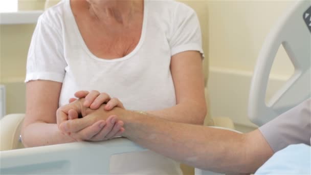 Старшая женщина гладит руку своего больного мужа — стоковое видео