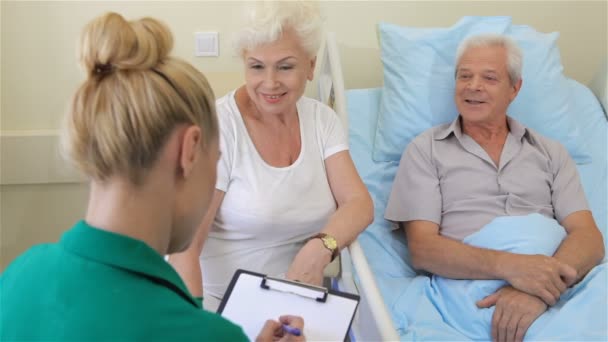 Verpleegkundige neemt nota van de stand van de gezondheid van de senior mannelijke patiënt — Stockvideo