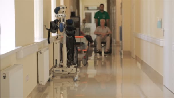 Доктор штовхає інвалідне крісло з пацієнтом у лікарні — стокове відео