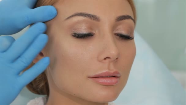 Kosmetikerin dehnt die Haut an der Schläfe des Klienten — Stockvideo