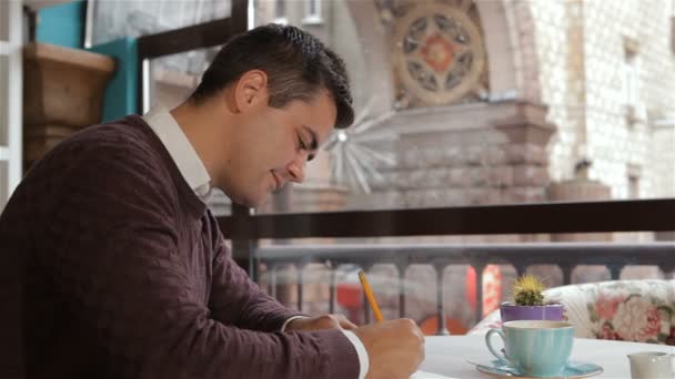 Defterindeki çiziminden kafede adam yazıyor — Stok video
