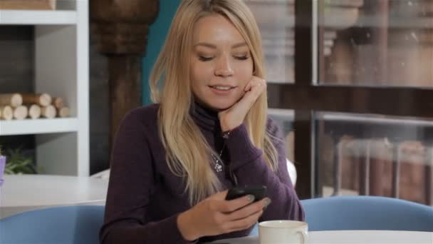 Chica utiliza su teléfono inteligente en el café — Vídeos de Stock