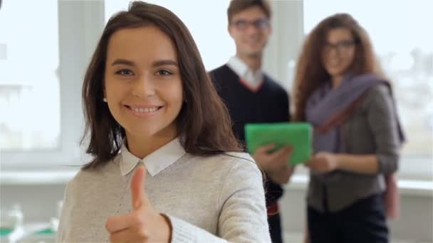 Ragazza sorridente gesti di buona qualità davanti a uomo e donna con tablet — Video Stock