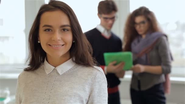 Hombre y mujer miren la tableta detrás de la chica sonriente en la oficina — Vídeos de Stock