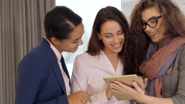 Three women looking at the tablet at the office
