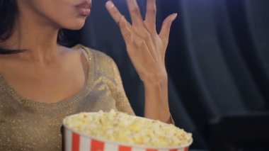 Kadın sinema salonu, patlamış mısır parmaklarını koyar