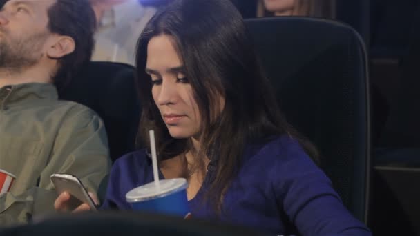 Girl uses smartphone at the movie theater — Stock Video
