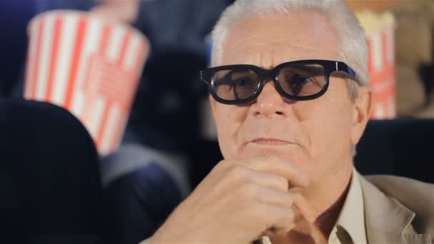 Hombre mayor se frota la barbilla en el cine — Vídeos de Stock