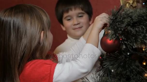 小さな男の子は、クリスマス ツリーに飾る弓をハングアップします。 — ストック動画