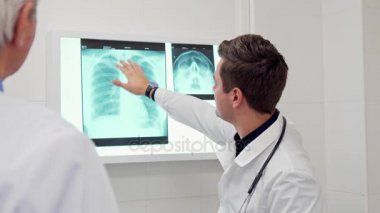 Erkek doktor röntgende meslektaşı için bir şey gösterir