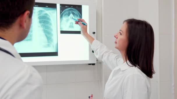 Жінка-лікар вказує олівець на рентген голови людини — стокове відео