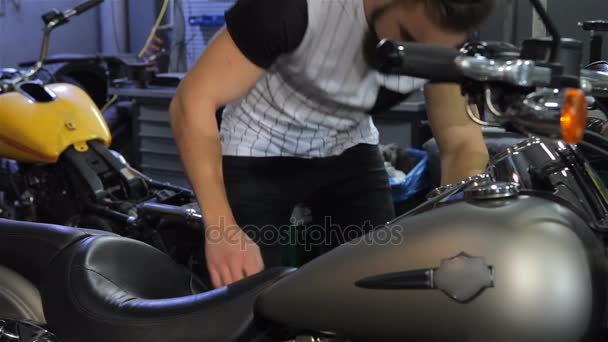 Homem agacha perto do helicóptero na oficina de motocicletas — Vídeo de Stock