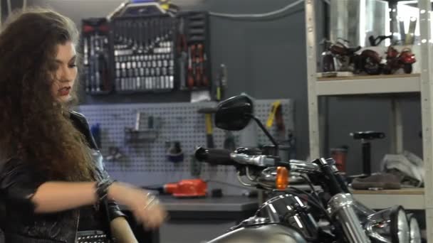 Femme motard bouge ses cheveux à l'atelier de moto — Video