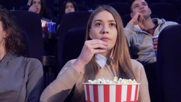 Menina lentamente coloca as pipocas em sua boca no cinema — Vídeo de Stock