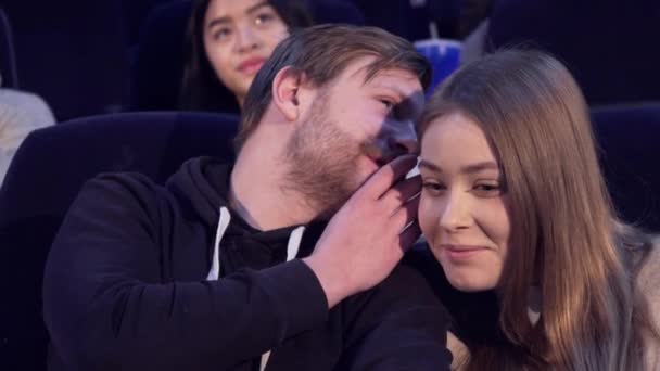 Man whisper something to his girlfriend at the movie theater — Stock Video