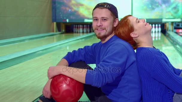 Jongen en meisje zittend op de vloer op de bowlingbaan — Stockvideo
