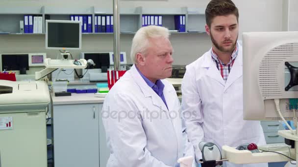 Два чоловіки дивляться на монітор у лабораторії — стокове відео