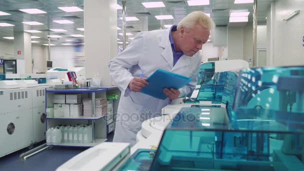 Homem fica perto de dispositivos de laboratório — Vídeo de Stock