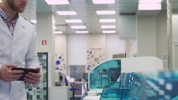 Man kontrollerar arbetet i lab-enhet med tablett — Stockvideo