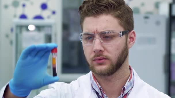 Чоловік тримає пробірку в руці в лабораторії — стокове відео
