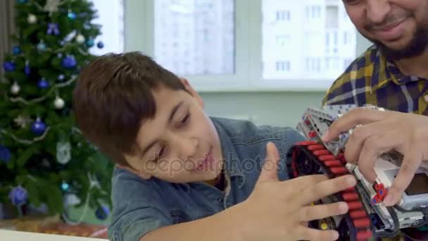 Мальчик кладет указательный палец под трек игрушечного квадроцикла — стоковое видео