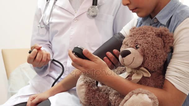 Un primer plano muestra cómo un médico mide la presión de una niña — Vídeos de Stock