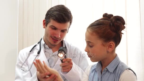 Гарна маленька дівчинка сидить тихо, поки лікар оглядає її — стокове відео