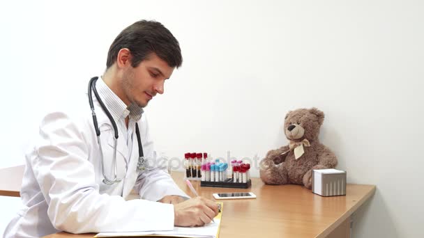 Der Kinderarzt schreibt Informationen über den Patienten auf — Stockvideo