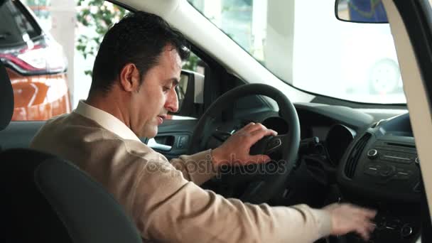 Un homme solide est habitué à l'intérieur d'une nouvelle voiture — Video