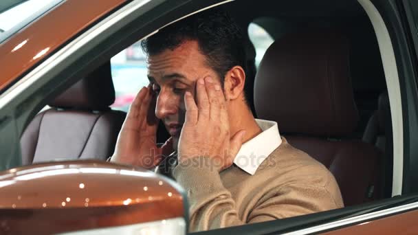 De trieste man heeft een scherpe hoofdpijn terwijl hij in de auto zit — Stockvideo