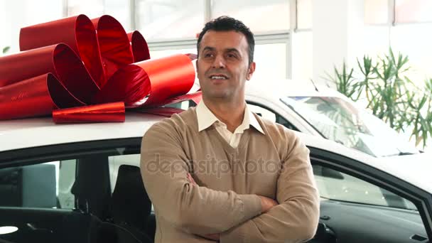 Un homme solide se tient sur le fond d'une voiture avec un arc cadeau — Video