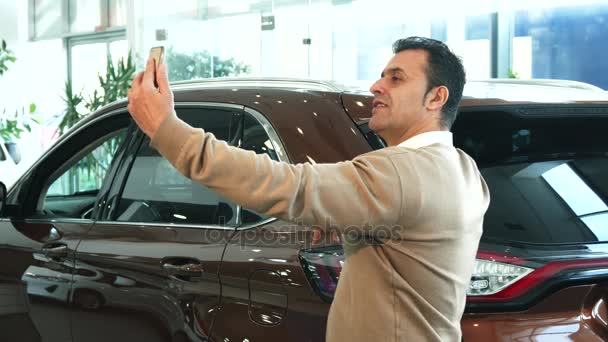 A nice man makes selfie on the background of a new car — Stock Video