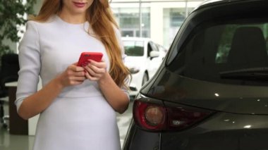 Neşeli bir kadının arabasını yakınındaki akıllı telefon ayakta kullanarak atış kırpılmış