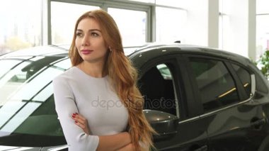 Sersem bir yeni araba galerisinde eğilerek gülümseyen neşeli genç kadın