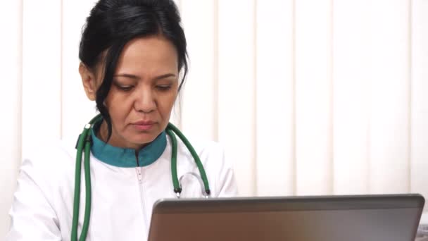 Крупный план красивой азиатской зрелой женщины врач работает на ее ноутбуке — стоковое видео