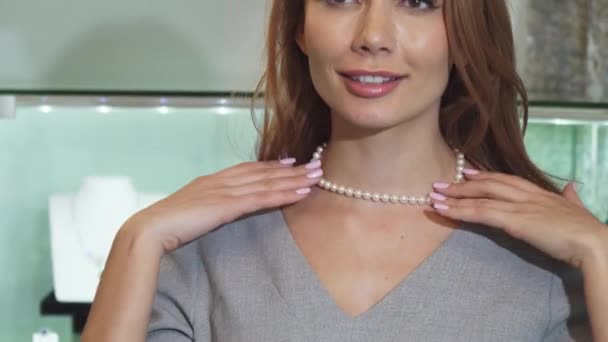 Close up de uma linda mulher feliz tentando em um colar de pérolas — Vídeo de Stock