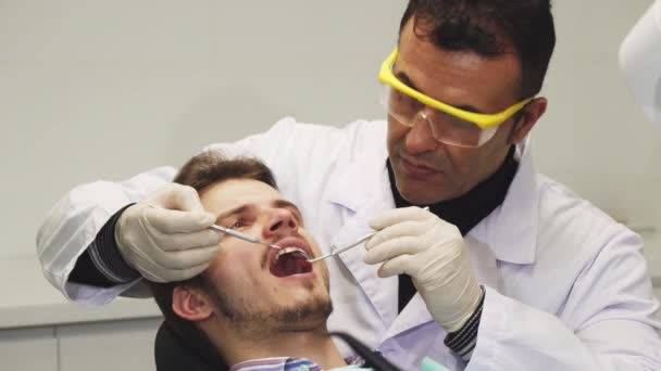 Primo piano di un dentista professionista che esamina i denti del suo paziente — Video Stock