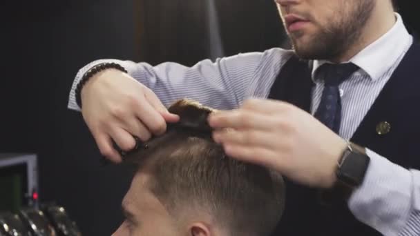 Cropepd tiro de um barbeiro profissional corte de cabelo de seu cliente masculino — Vídeo de Stock