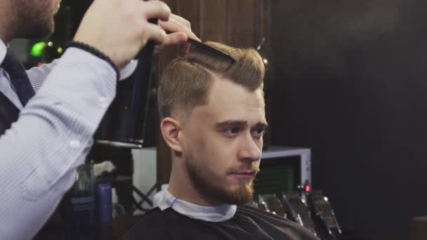 Barbeiro profissional usando laca e secador de cabelo styling cabelo de um cliente — Vídeo de Stock
