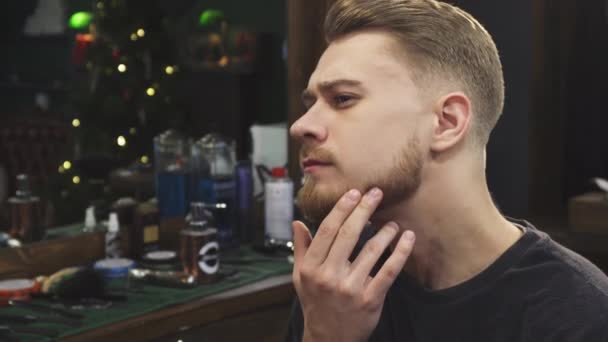 bel homme barbu examiner sa nouvelle coupe de cheveux au salon de coiffure 