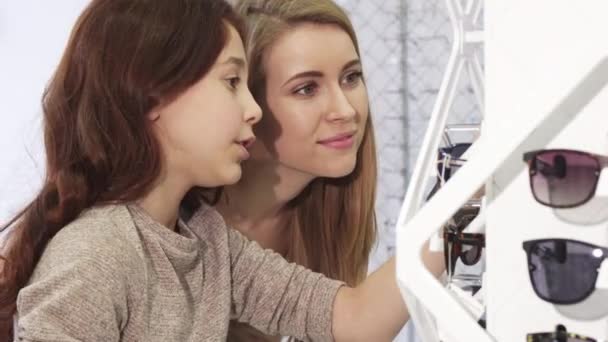 Söt liten flicka att välja solglasögon med hennes äldre syster i butiken — Stockvideo