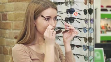 Neşeli güzel kadın güneş gözlüğü optometrist mağazasında çalışıyor