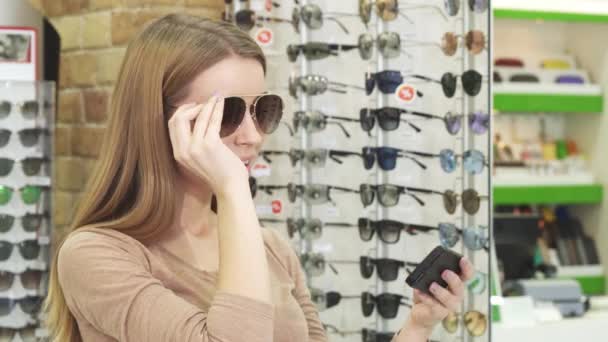 Счастливая молодая женщина делает селфи во время покупки очков — стоковое видео