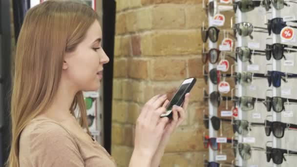 Hermosa mujer tomando fotos de gafas de sol en la pantalla de la tienda — Vídeo de stock